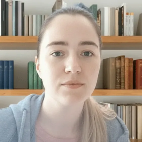 Michelle Becker, Geschäftsführung bei Shop4Pets, mit hellem Haar und grauem Hoodie vor einem Bücherregal, freundlicher Blick und klarer Ausdruck.