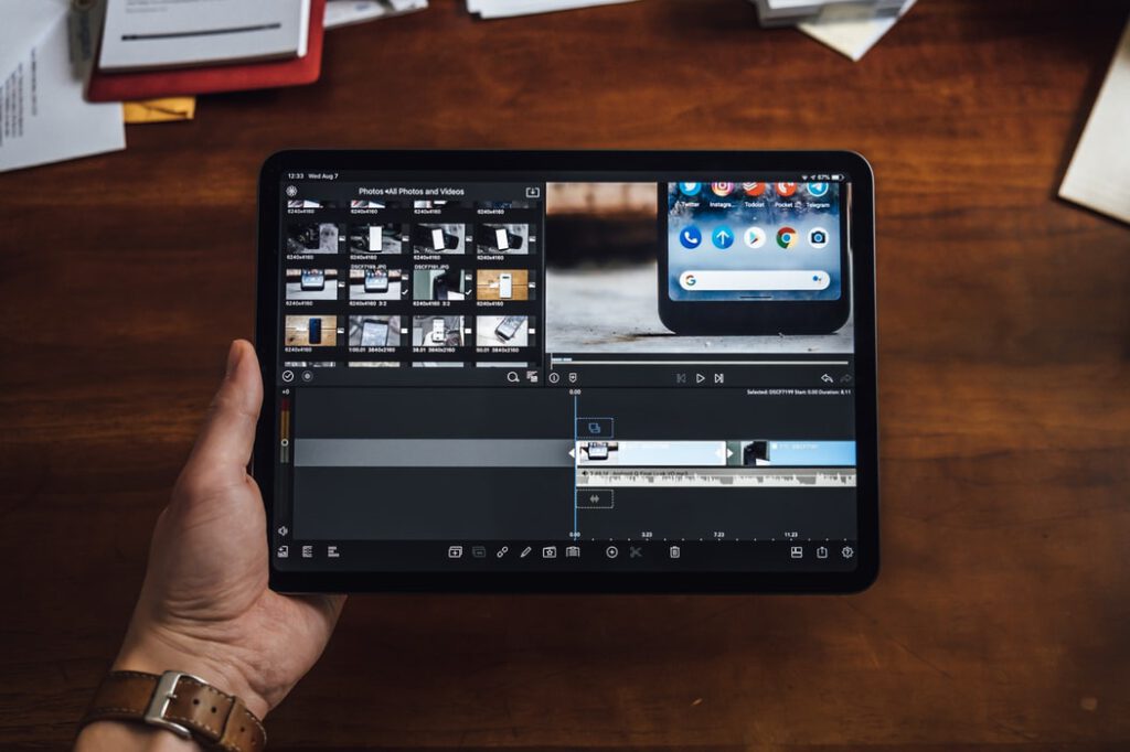 Tablet mit Videobearbeitung auf dunklem Interface und braunem Holztisch, Vorschauen und Timeline; Videos und Fotos bearbeiten – ganz einfach mit VSCO Cam, PicPlayPost