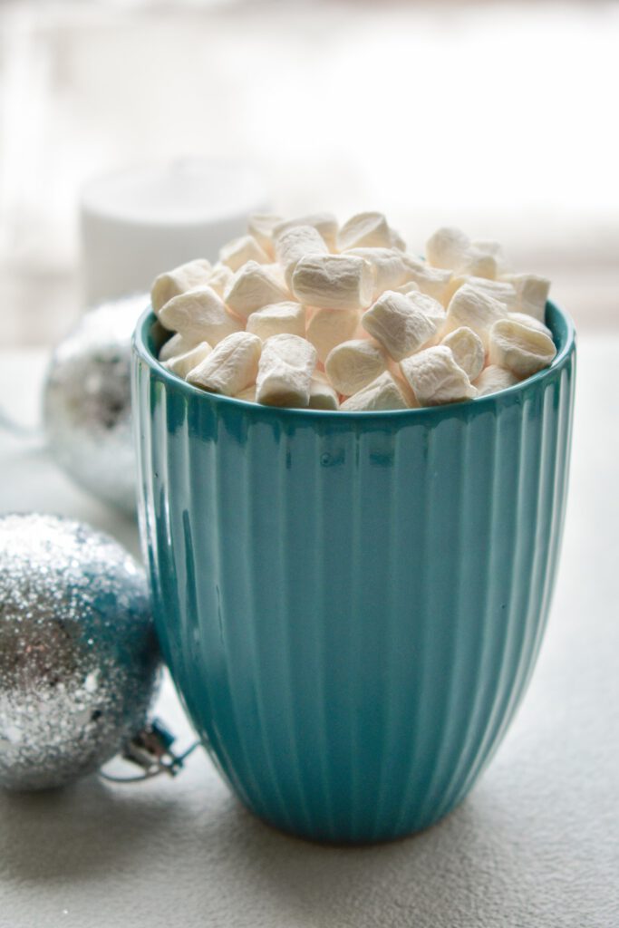 Teale Keramikschale mit weißen, weichen Marshmallows auf hellem Untergrund – Anknüpfung an den Tag der gerösteten Marshmallows